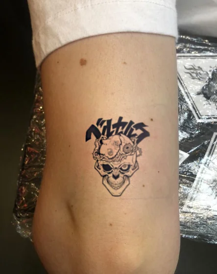 Anime Berserk skull tattoo idea for women on upper arm