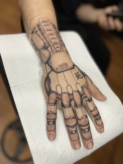 Biomechanical robotic hand tattoo idea for men on hand.