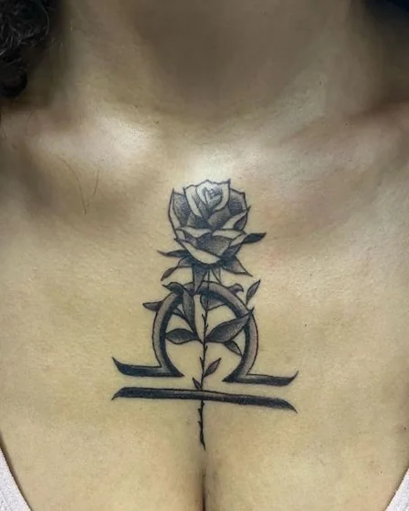 Black And Grey rose and Libra tattoo design for women on sternum.
