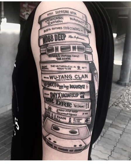 Black and Grey Realism music cassette tape tattoo design for men on upper arm