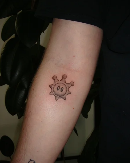 Black and grey linework Super Mario Star tattoo design for men on upper arm