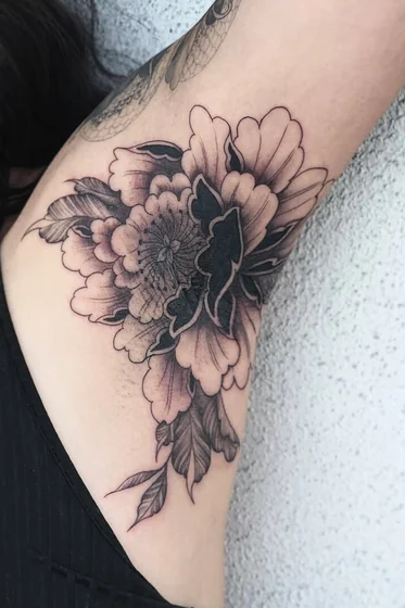 Black and grey neo-traditional flower tattoo idea for women on upper arm
