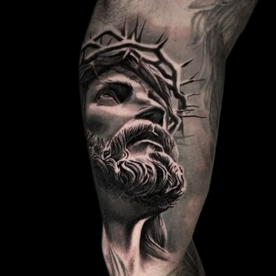 Black and grey realistic Jesus tattoo design for men on upper arm