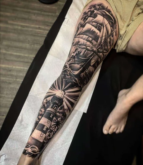 Black and grey realistic ship, lighthouse tattoo for men on leg