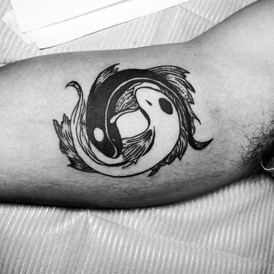 Blackwork Yin Yang fish tattoo idea for men on bicep