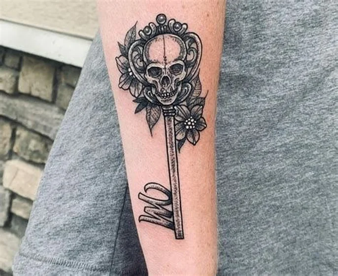 Blackwork and Black And Grey skull, key, floral tattoo for women on forearm.
