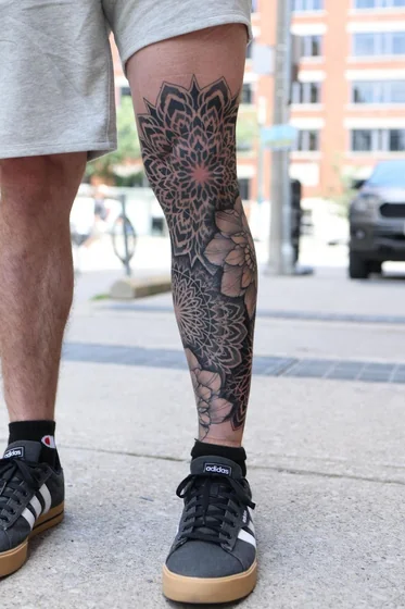 Blackwork geometric mandala and floral tattoo idea for men on knee and leg