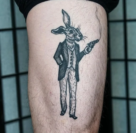 Blackwork rabbit with gun tattoo idea for men on thigh.