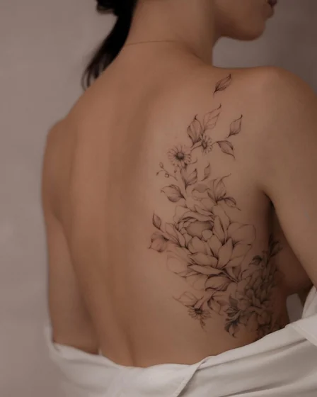 Delicate fine line floral tattoo design for women on back and shoulder