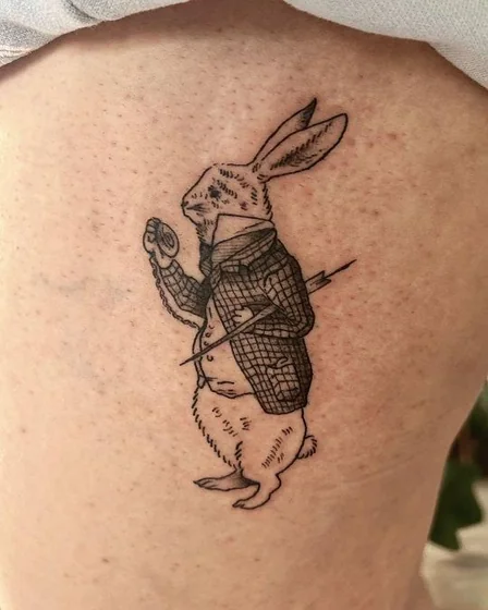 Fine Line Black And Grey Alice In Wonderland rabbit tattoo for men and women on thigh