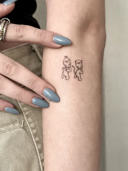 Fine Line Minimalist Angel and Devil tattoo design for women on Upper Arm