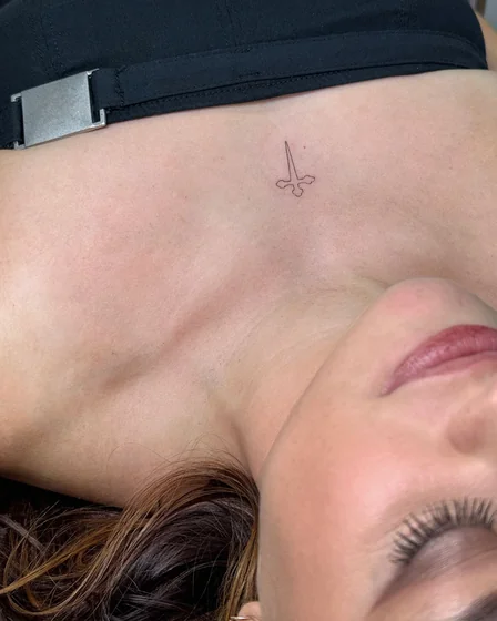 Fine Line Minimalist Sword tattoo design for women on Sternum
