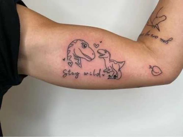 Fine Line Patchwork dinosaur and heart tattoo for women on upper arm.