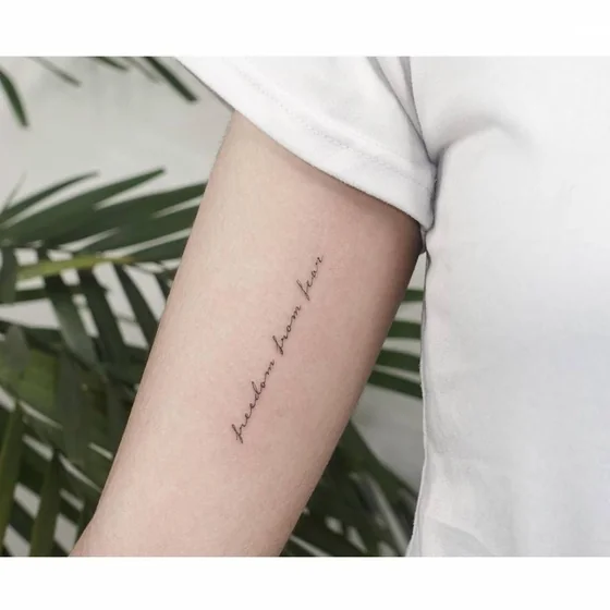 Fine Line Script 'freedom from fear' tattoo idea for women on upper arm