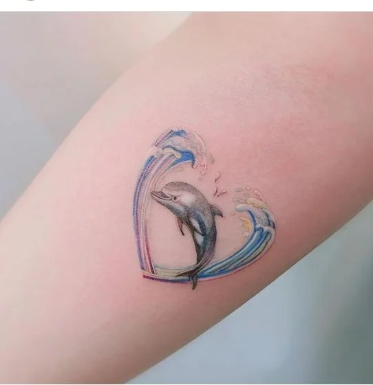 Fine Line dolphin and wave heart tattoo design for women on forearm