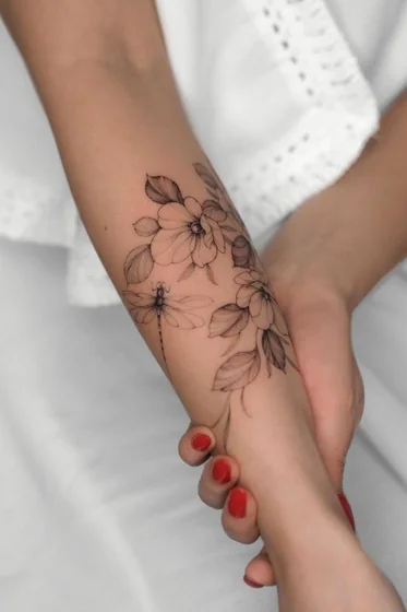 Fine Line floral dragonfly tattoo idea for women on forearm.