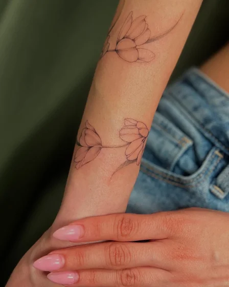 Fine Line minimalist floral tattoo design for women on forearm and wrist