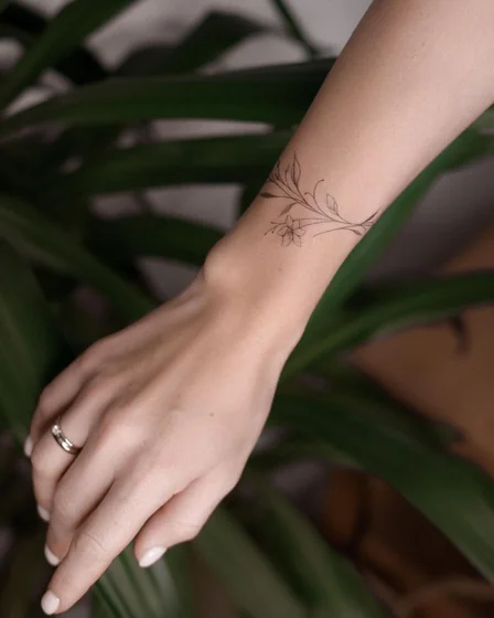 Fine Line minimalist floral vine tattoo design for women on forearm