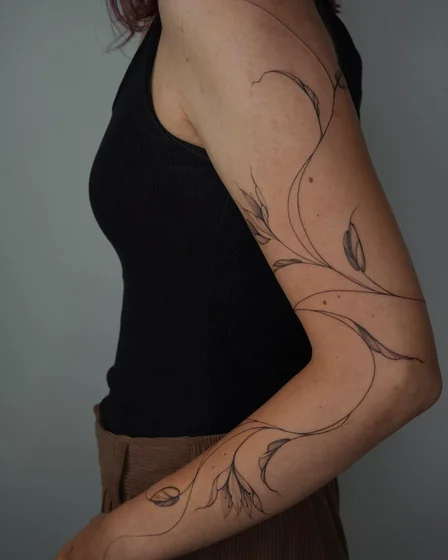 Fine Line minimalist floral vine tattoo design for women on upper arm
