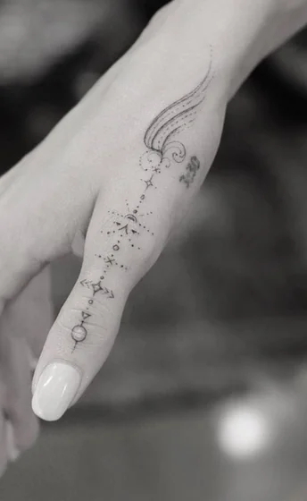 Fine line and dotwork star and moon celestial path tattoo design for women on finger and hand