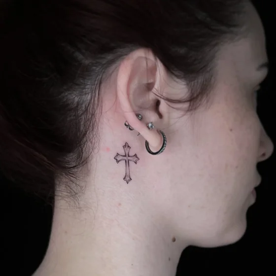 Fine line cross tattoo idea for women on neck behind the ear