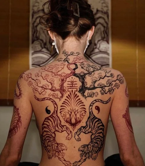 Fine line linework tiger, lotus, tree, Chinese character tattoo for women on back.