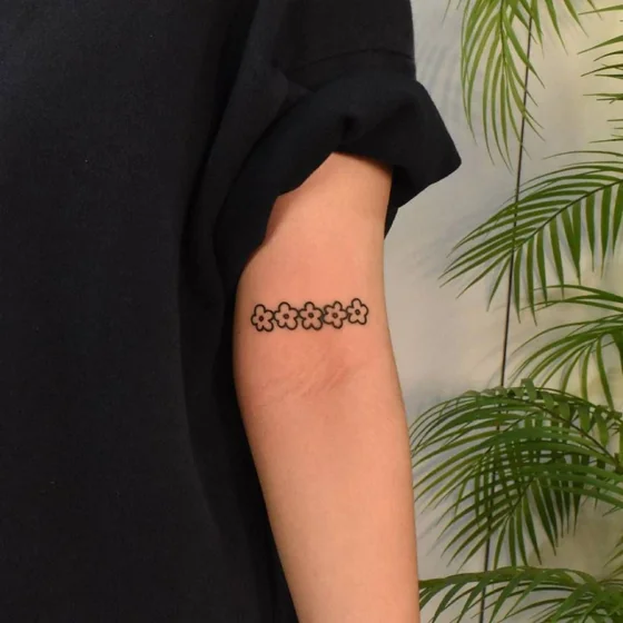 Fine line minimalist flower tattoo design for women on bicep tattoo ideas