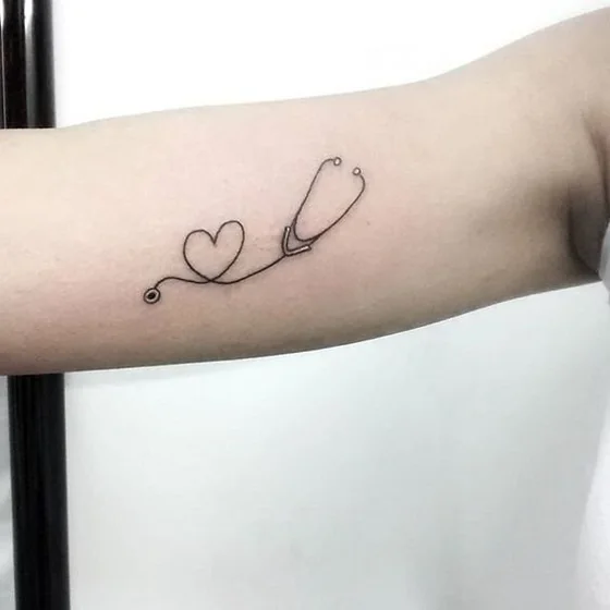 Fine line minimalist stethoscope heart tattoo for women on upper arm