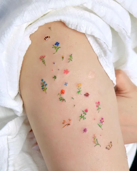 Fine line patchwork floral & insect tattoo for women on thigh