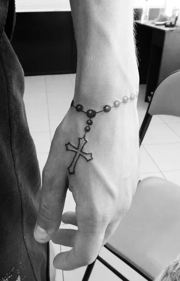 Fine line rosary cross tattoo design for men on hand and wrist.