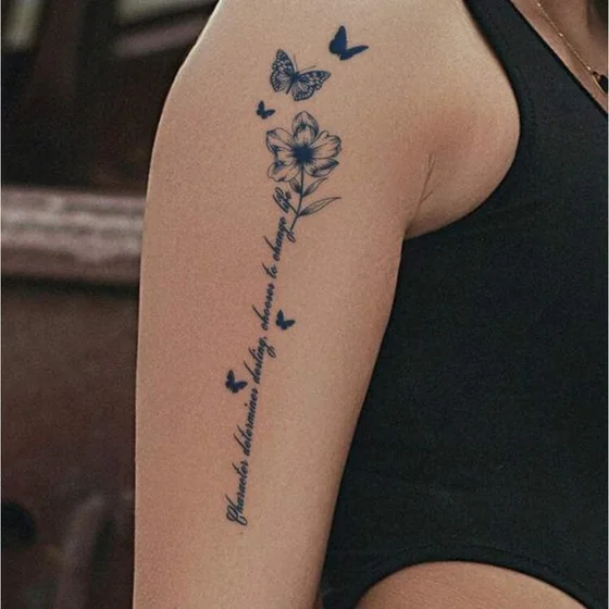 Fine line script flower and butterfly tattoo design for women on upper arm
