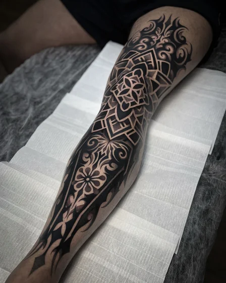 Geometric blackwork floral mandala tattoo design for men on leg
