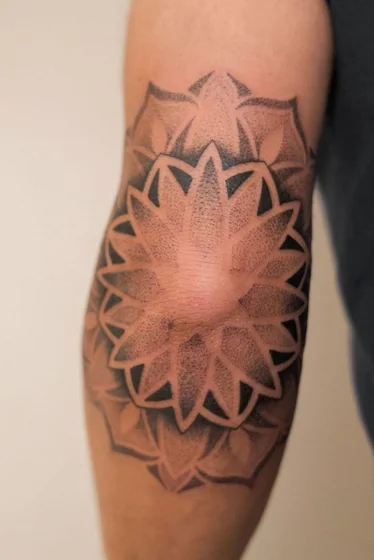 Geometric dotwork floral tattoo design for men and women on elbow