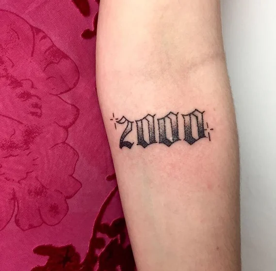 Gothic script '2000' tattoo design on forearm