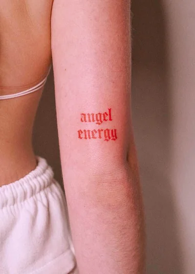 Gothic script 'angel energy' tattoo idea for women on upper arm