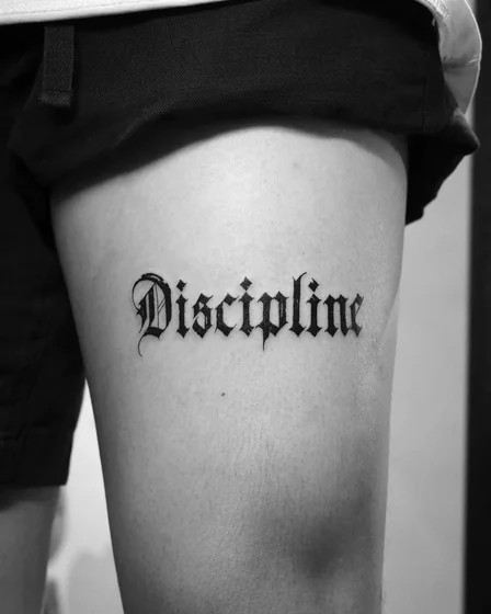 Gothic script word tattoo design for men and women on thigh
