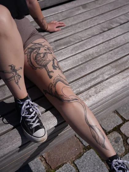 Linework sketch dragon and scarecrow tattoo for women on leg.