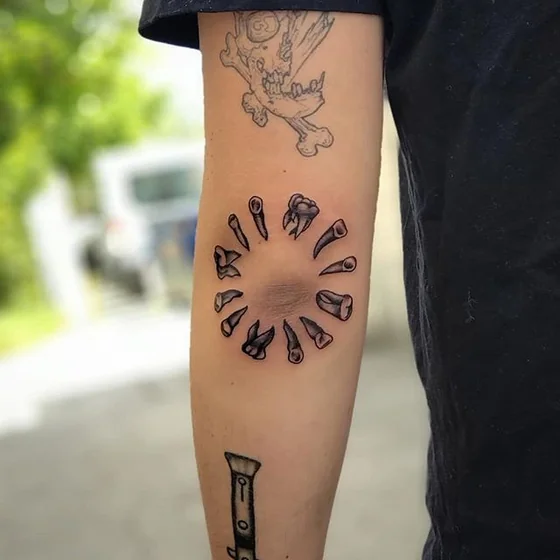 Men's Patchwork Blackwork skull and teeth tattoo on elbow and forearm.
