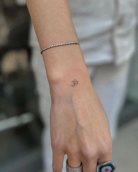 Minimalist Om symbol fine line tattoo for women on wrist