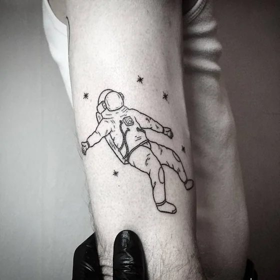 Minimalist astronaut in space tattoo design for men on upper arm