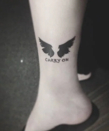 Minimalist blackwork wing and quote tattoo for women on ankle