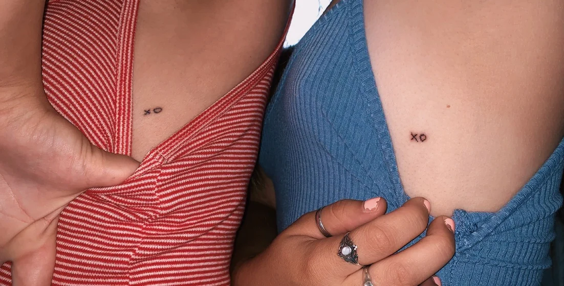 Minimalist fine line XO tattoo design for women on chest