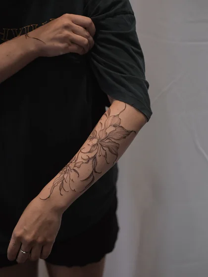 Minimalist fine line floral tattoo design for women on forearm