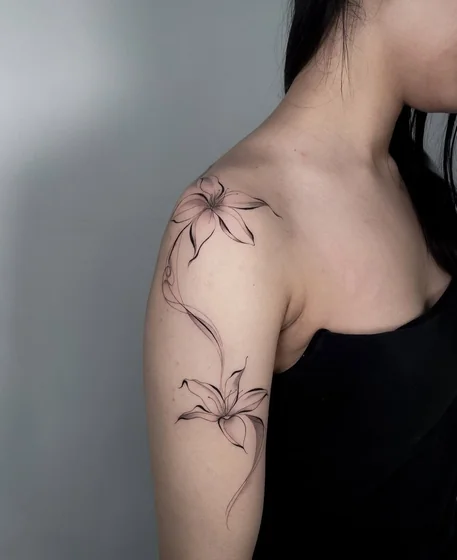 Minimalist fine line floral tattoo design for women on shoulder upper arm