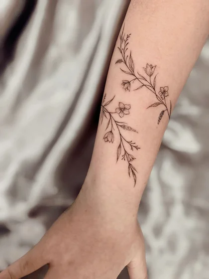 Minimalist fine line floral vine tattoo for women on forearm