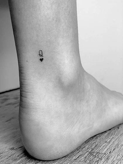 Minimalist fine line heart and letter Q tattoo design for women on ankle