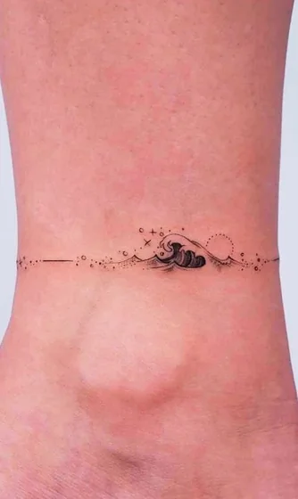 Minimalist fine line ocean, sun, star tattoo for women on ankle.