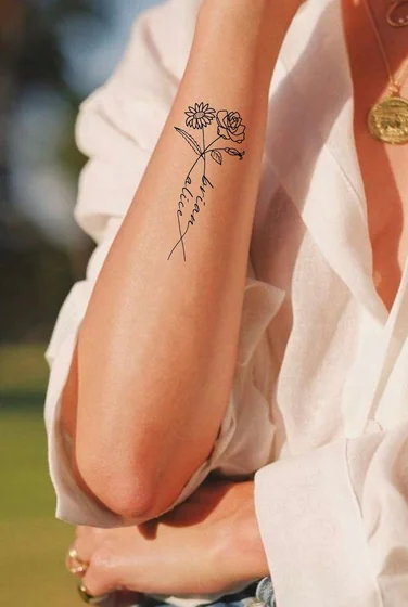 Minimalist fine line rose, daisy, and name tattoo design for women on forearm