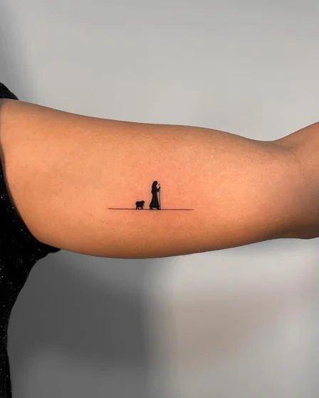 Minimalist fine line shepherd and sheep tattoo design for women on bicep.