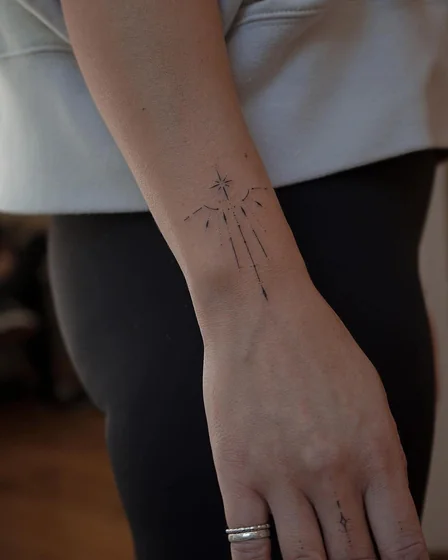Minimalist fine line star compass tattoo for women on forearm